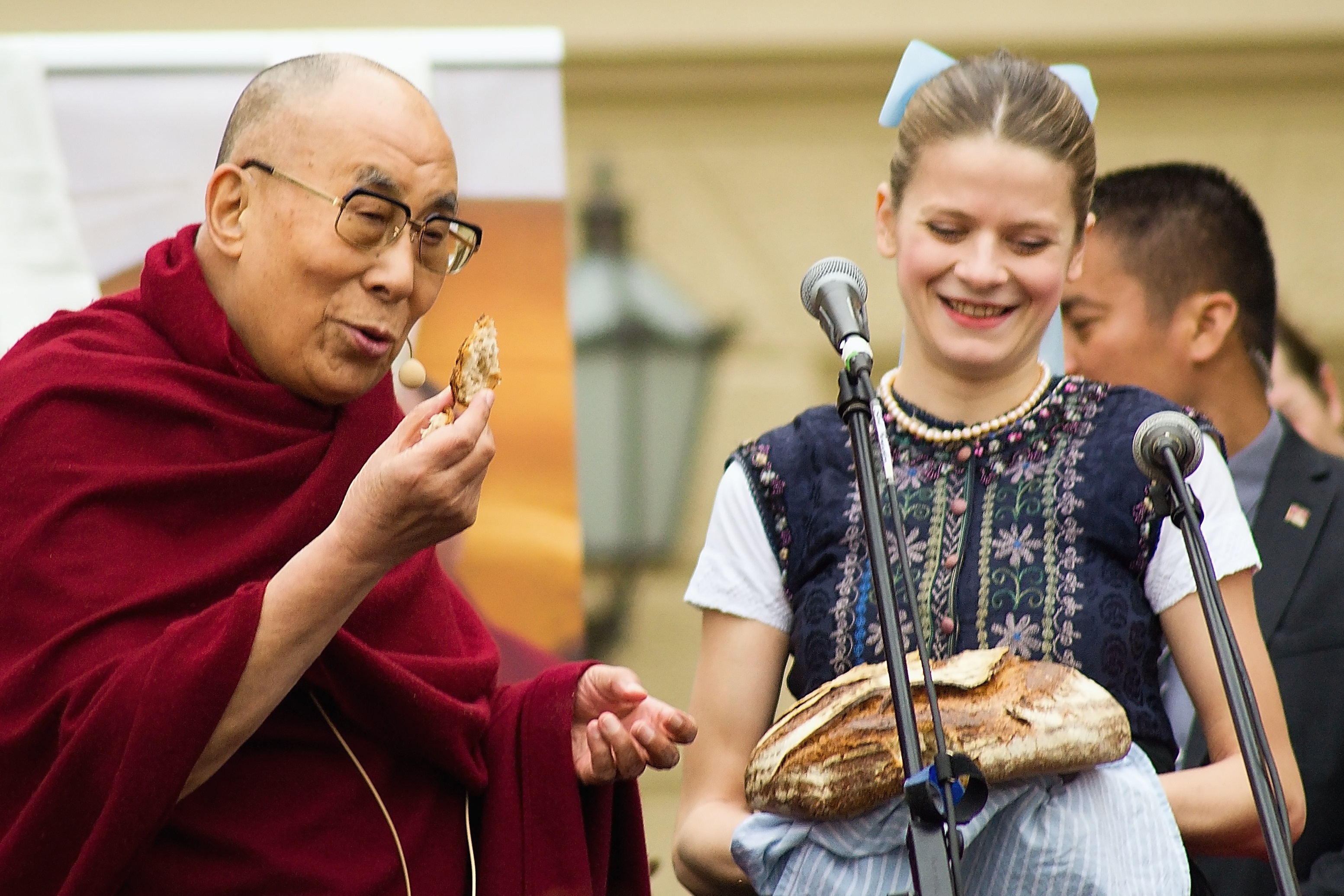 Dalajláma ochutnává český chléb přinesený ženou v kroji