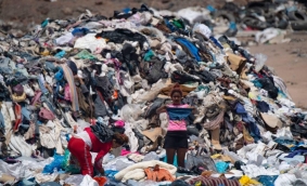 Ženy probírající oblečení v hromadách nepoužitých oděvů